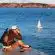 man sitting on dock taking photo of sea